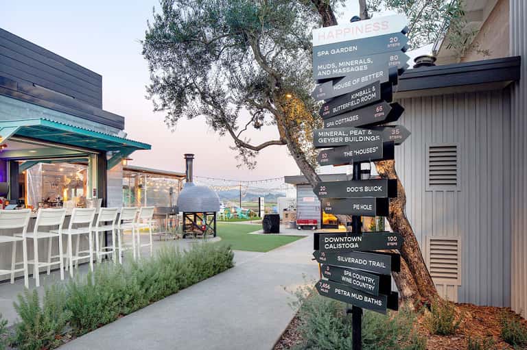 Outdoor spa resort grounds with directional signage, seating areas, and valley views
