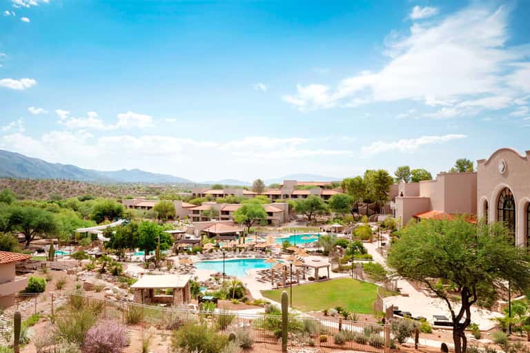 Desert resort with multiple pools, rustic buildings, and mountain landscape views