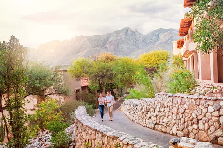 Mountain lodge courtyard with rustic stone pathways, Spanish colonial architecture, and lush vegetation