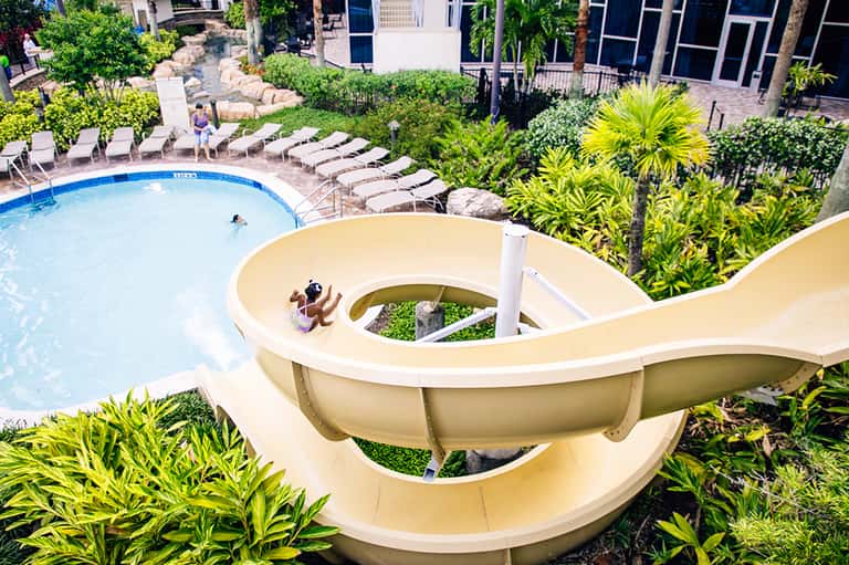 Aerial view of resort with white water slide, swimming pool, tropical landscaping and guest buildings