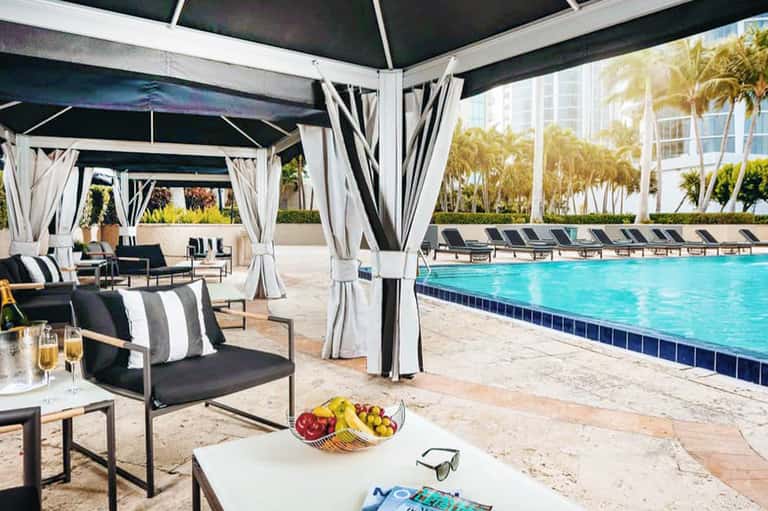 Modern cabana lounge with black and white striped seating overlooking turquoise pool