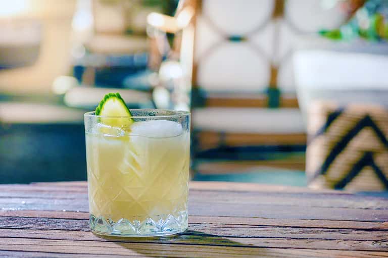 Refreshing citrus cocktail with lime garnish on wooden poolside table