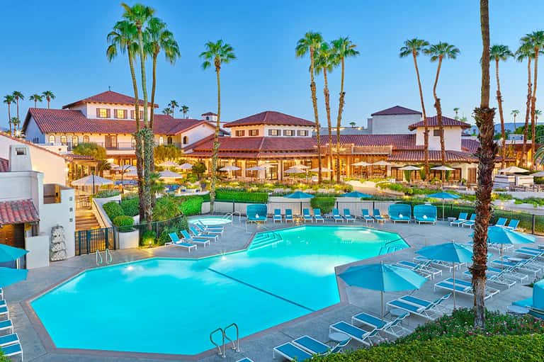 Luxury resort with multiple pools, palm trees, and Spanish-style architecture