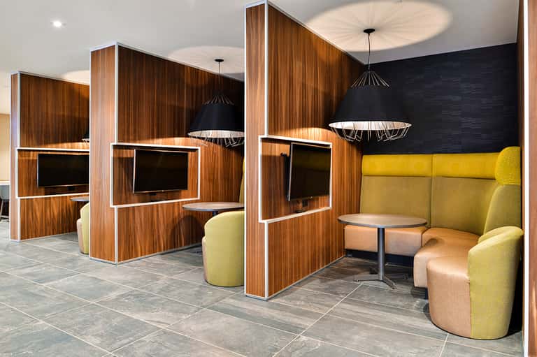 Modern hotel meeting spaces with wood partitions, yellow seating, and pendant lighting