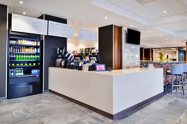 Hotel café counter with beverage cooler, menu boards, and service area with modern design