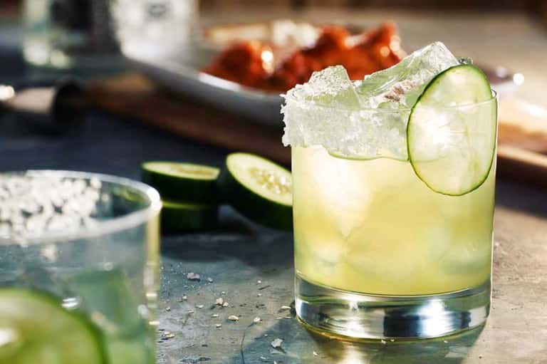 Refreshing lime cocktail with ice and cucumber slice on outdoor countertop