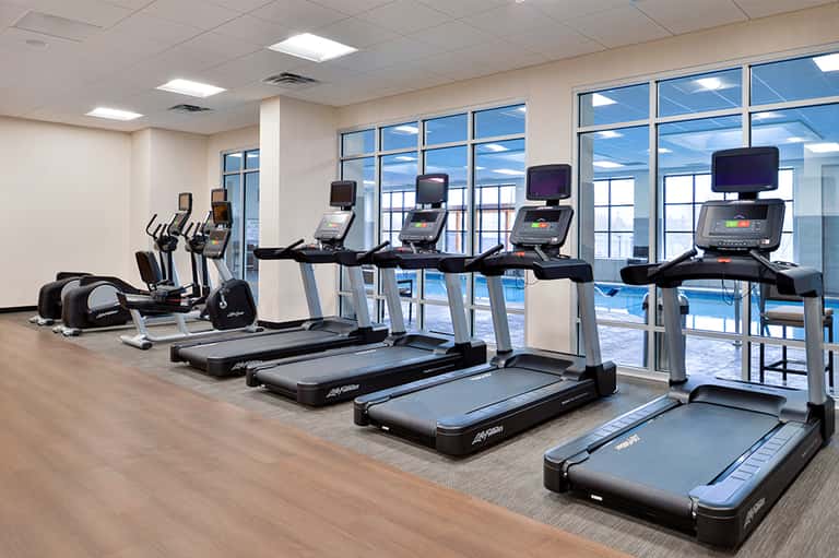 Modern hotel fitness center with treadmills, stationary bikes, and floor-to-ceiling windows