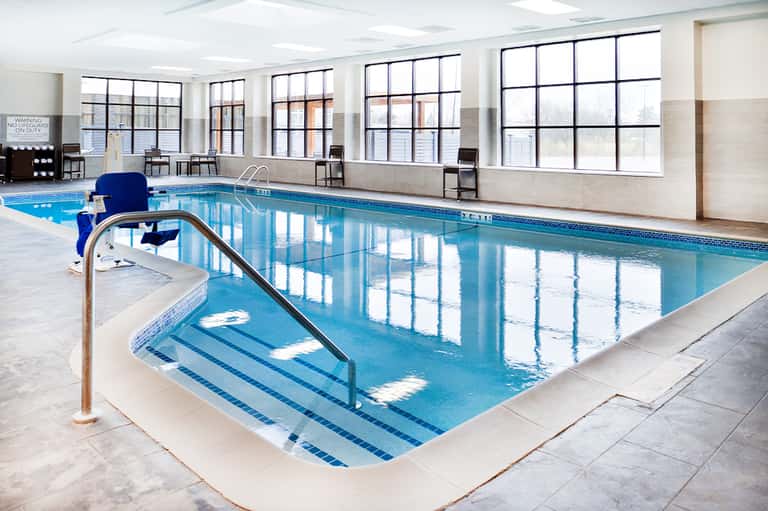 Indoor lap pool with lane markers, large windows, and modern facility design