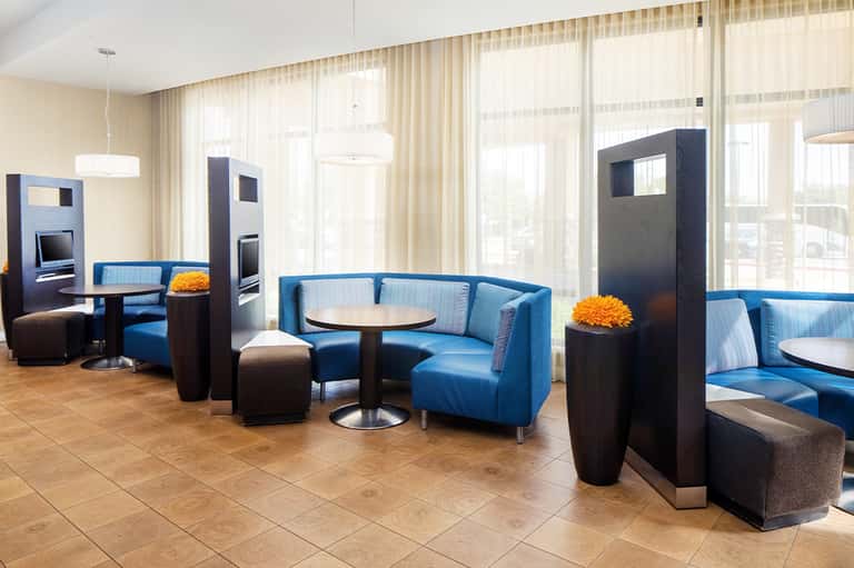 Modern hotel lounge with blue curved seating, dark accent pillars, and floor-to-ceiling windows