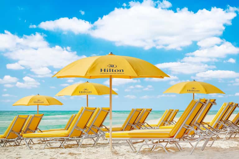 Beach lounge area with yellow umbrellas and chairs overlooking turquoise ocean water