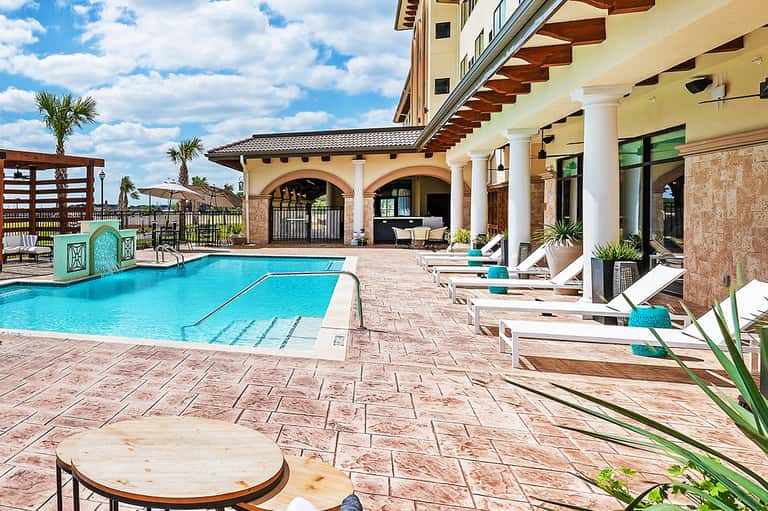 Luxury resort pool area with turquoise water, lounge chairs, covered pavilion, and manicured grounds
