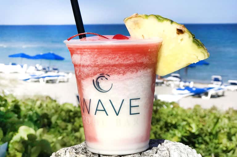 Tropical cocktail with pineapple garnish at beachfront bar overlooking ocean