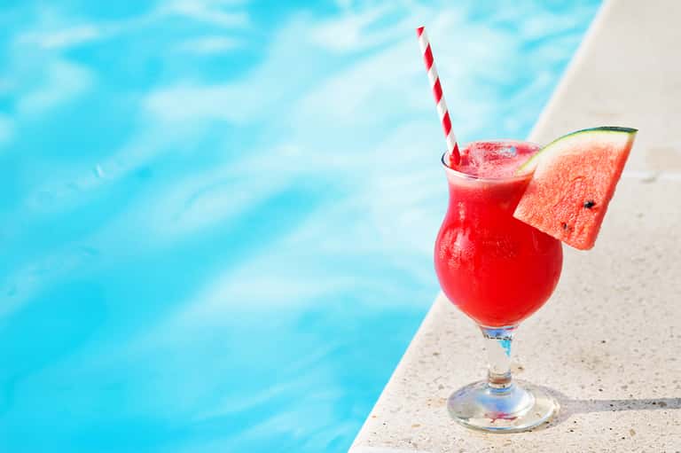 Red tropical cocktail with watermelon slice at poolside