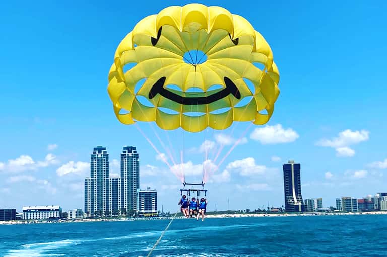 Parasailing adventure with yellow parachute over turquoise ocean near beachfront hotels