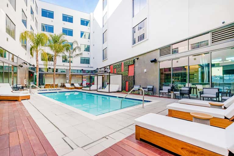 Resort courtyard with rectangular turquoise pool, lounge chairs, and surrounding white buildings