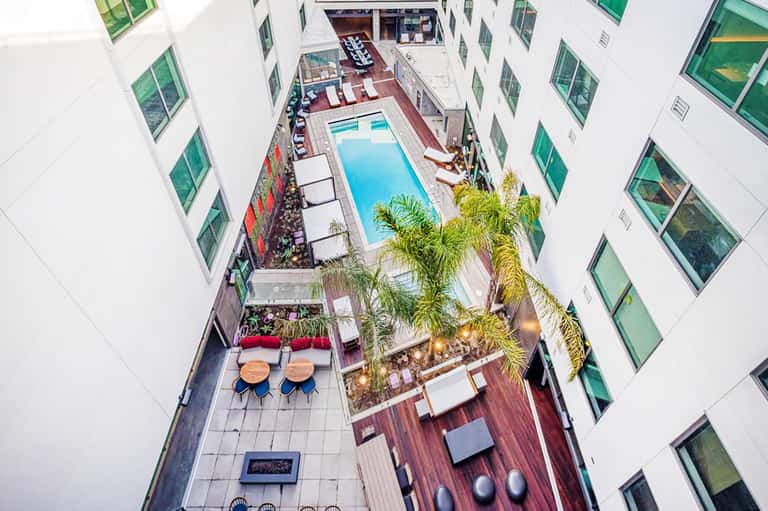 Overhead view of a narrow courtyard pool surrounded by white residential buildings with lounge chairs