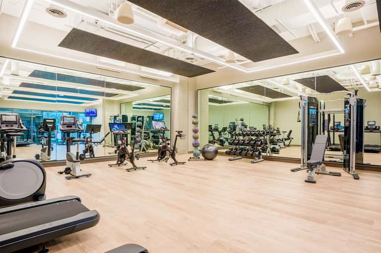Modern fitness center with cardio equipment, weights, and mirrored walls