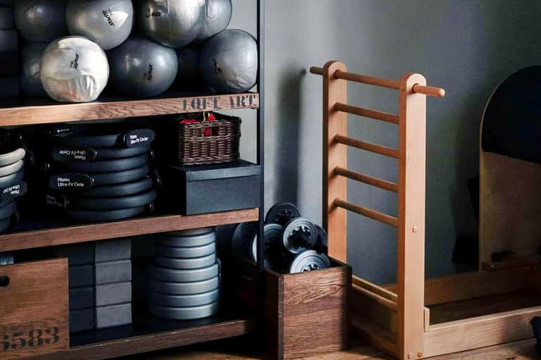 Fitness center interior with exercise equipment shelves and wooden training equipment