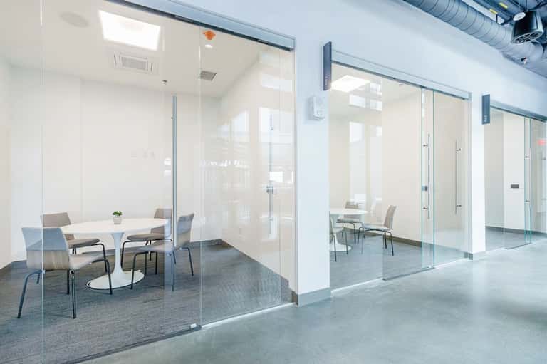 Modern office meeting rooms with glass walls, white walls, round table, and contemporary furnishings