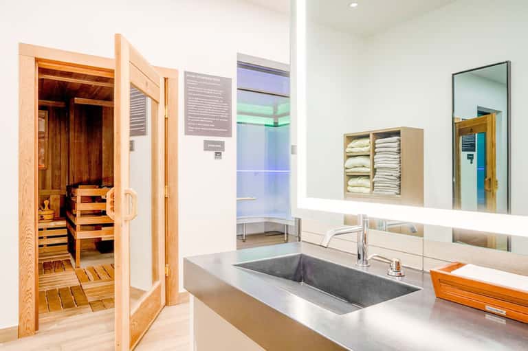 Spa bathroom with sauna, vessel sink, mirror, and towel storage shelving