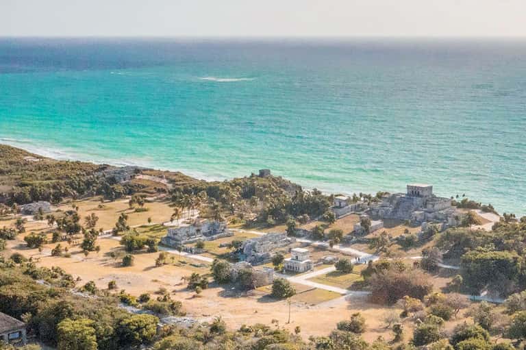 Coastal aerial view of beachfront resort with turquoise waters, sandy beach, and Mayan ruins