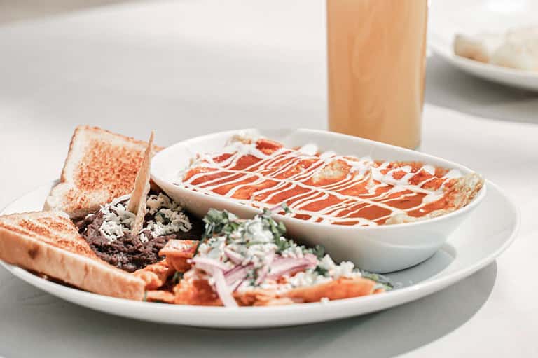 Gourmet seafood platter with crab toast, prawns, and sauce drizzle on white plate