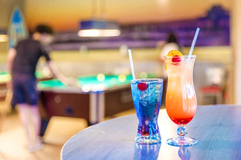 Colorful cocktails on bar counter with blurred recreation room in background