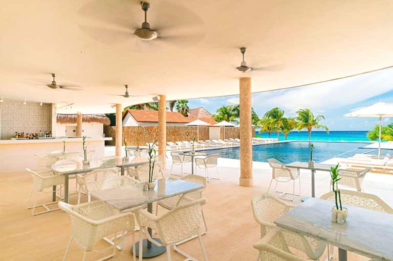 Beachfront restaurant pavilion with ocean views, lounge seating, and thatched roof details