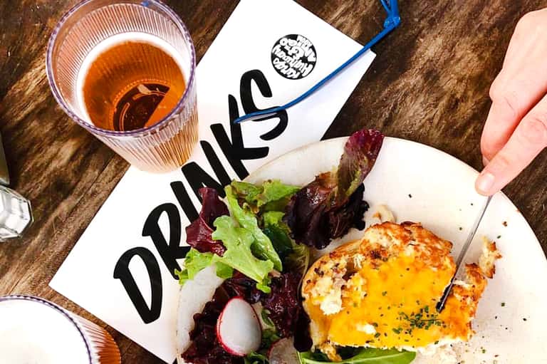 Gourmet dish with salad and sauce at Daniels restaurant with amber beverage on rustic wood table