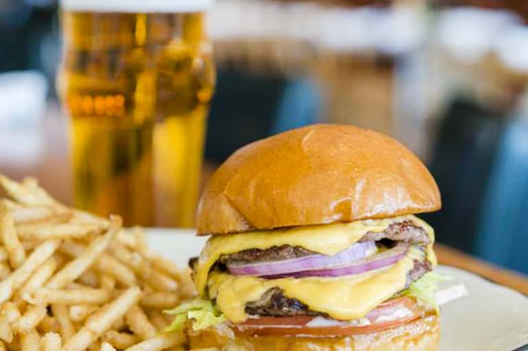 Double cheeseburger with tomato and onion, served with french fries and cold beer