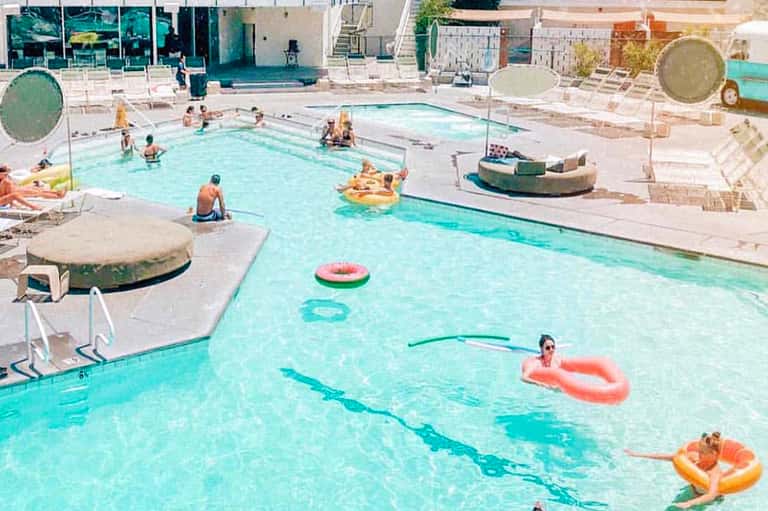 Resort pool with guests swimming and relaxing on colorful pool floats and lounge chairs