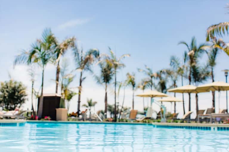 Blurred pool view with palm trees and white umbrellas at a tropical resort