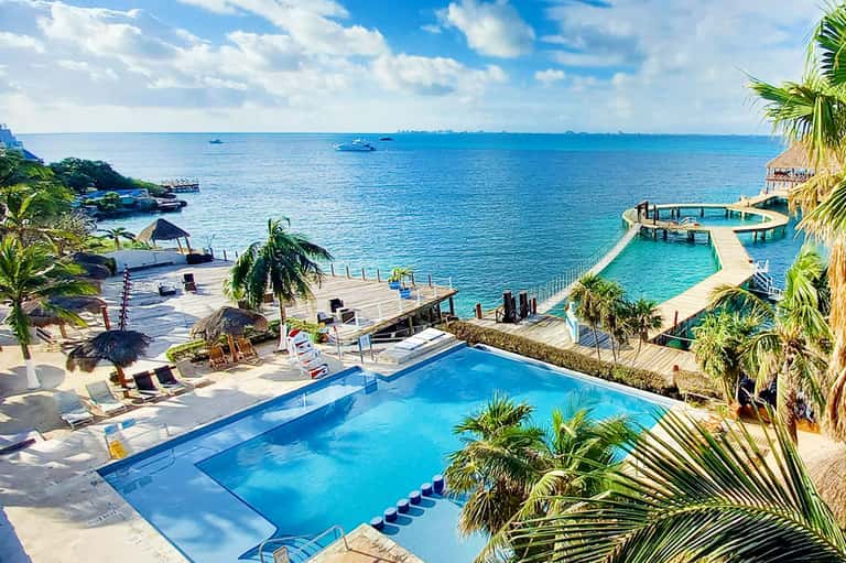 Beachfront resort with infinity pool overlooking turquoise ocean and palm trees