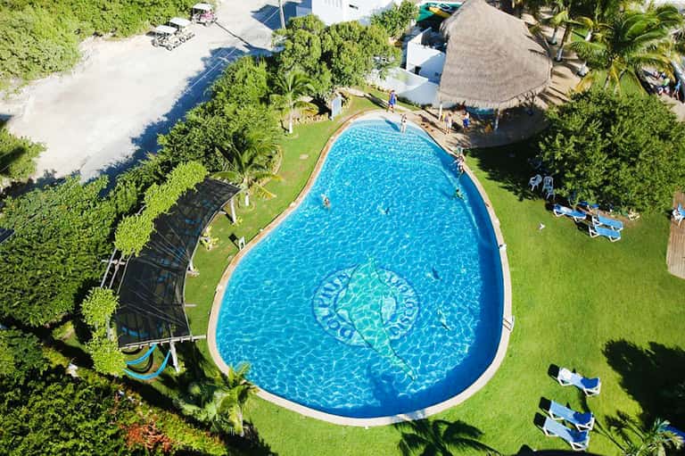 Aerial view of kidney-shaped resort pool nestled in tropical landscaping