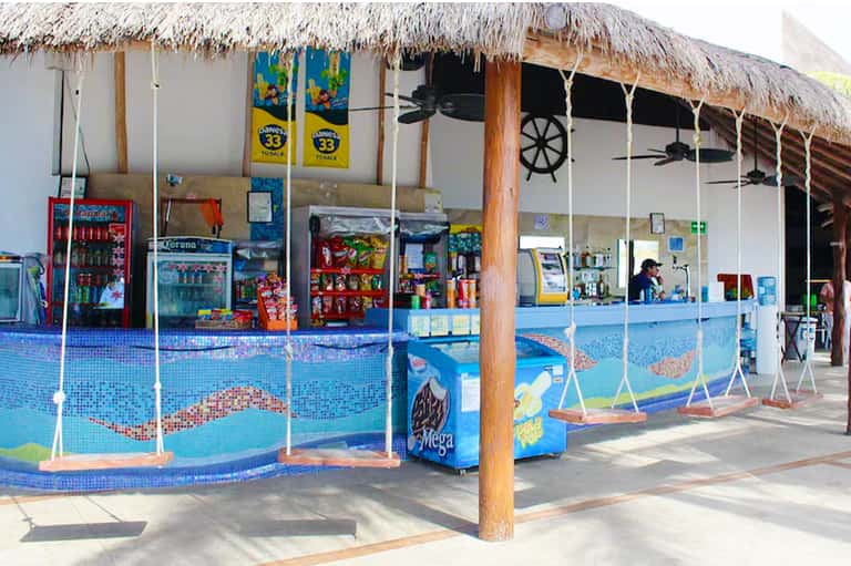 Thatched-roof pool bar with snacks and beverages, rope swings, and colorful mosaic tile design