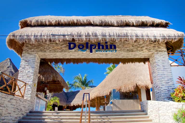 Dolphin Discovery entrance with thatched-roof architecture and white stone walls under clear sky