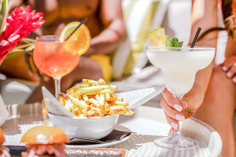 Colorful cocktails and appetizers on outdoor dining table with fresh flowers