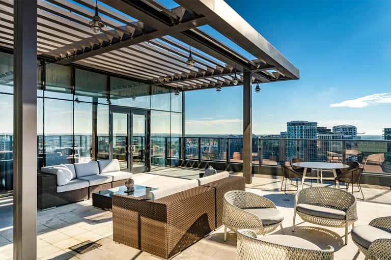 Modern rooftop terrace with lounge seating, glass railings, and city skyline views