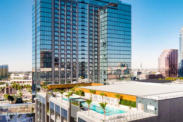 Urban high-rise hotel with rooftop pool overlooking city skyline at daytime
