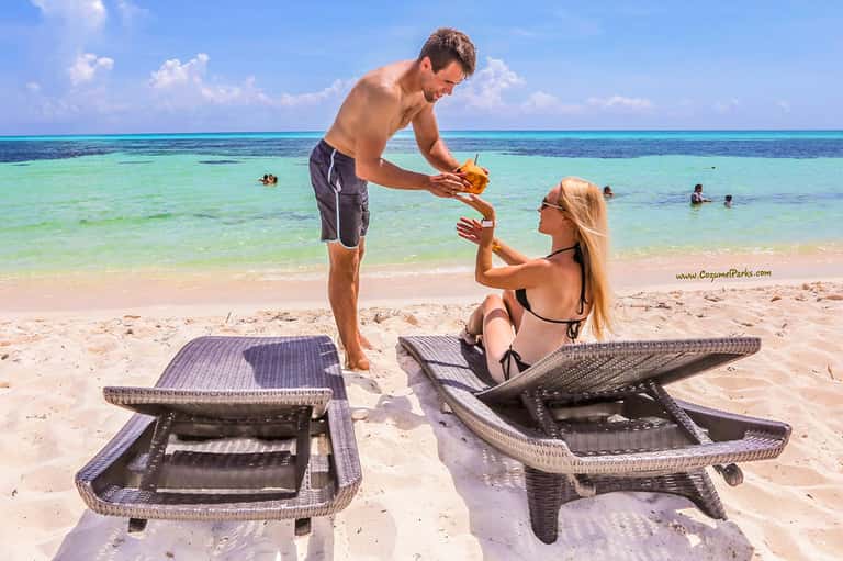Couple exchanging fruit on a pristine tropical beach with clear turquoise water