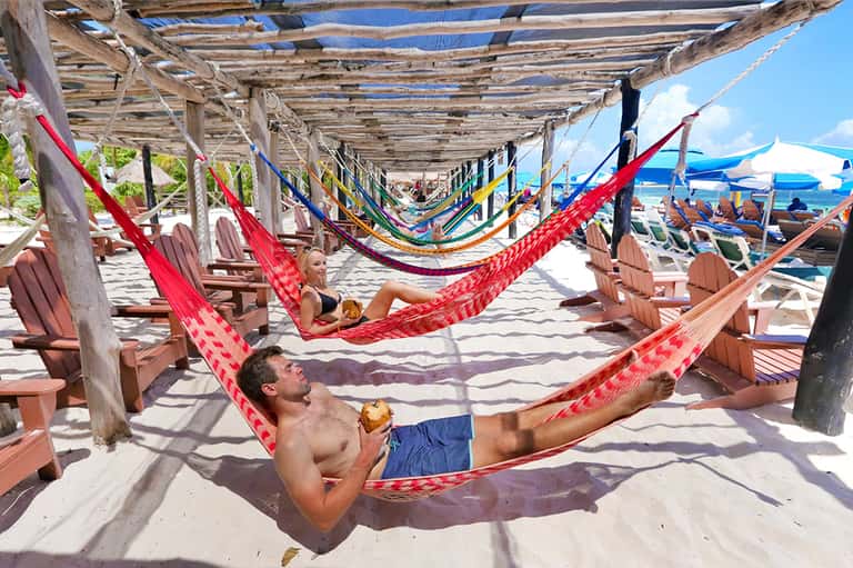 Beachfront hammock lounge with colorful hammocks, Adirondack chairs, and ocean view