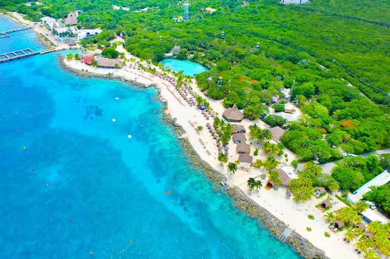 Aerial view of tropical beachfront resort with turquoise ocean and lush vegetation