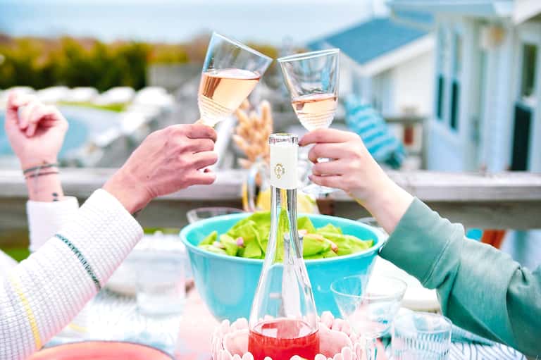 Two people toasting with wine glasses at outdoor poolside dining area