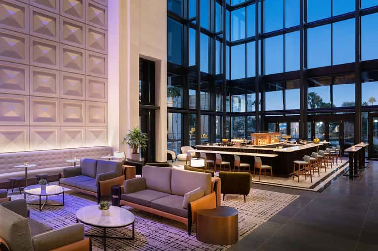 Elegant hotel bar lounge with geometric wall panels, modern seating, and floor-to-ceiling windows
