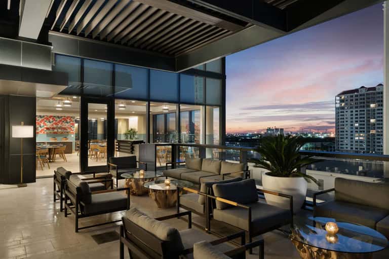 Modern high-rise terrace lounge at sunset with contemporary furniture and cityscape views