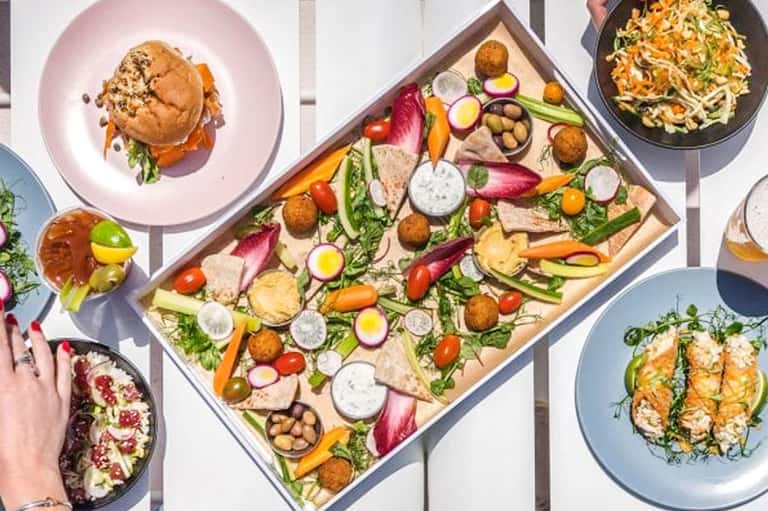 Overhead view of gourmet dishes and fresh ingredient board on white surface
