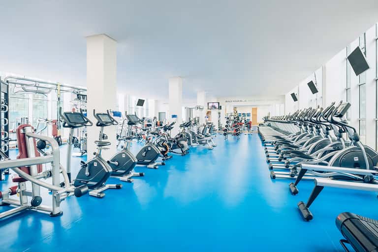 State-of-the-art fitness center with rows of exercise bikes and cardio equipment on blue flooring