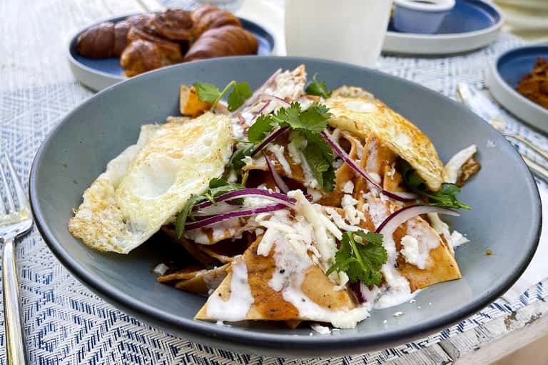 Plated breakfast dish with omelet, crispy potatoes, and fresh herbs