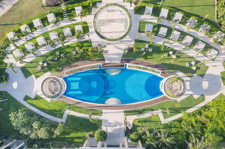 Aerial view of luxury resort with kidney-shaped pool, lounge chairs, and manicured green lawns