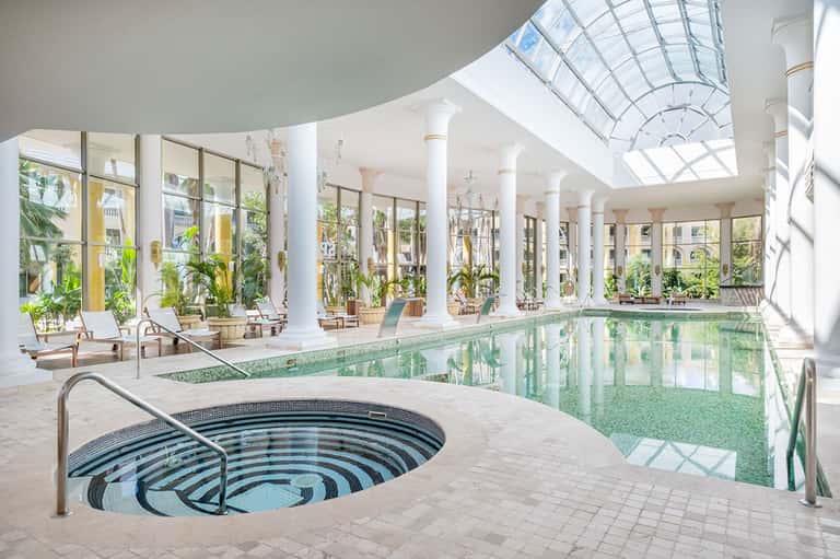 Indoor spa area with lap pool, circular hot tub, skylights, and columned architecture